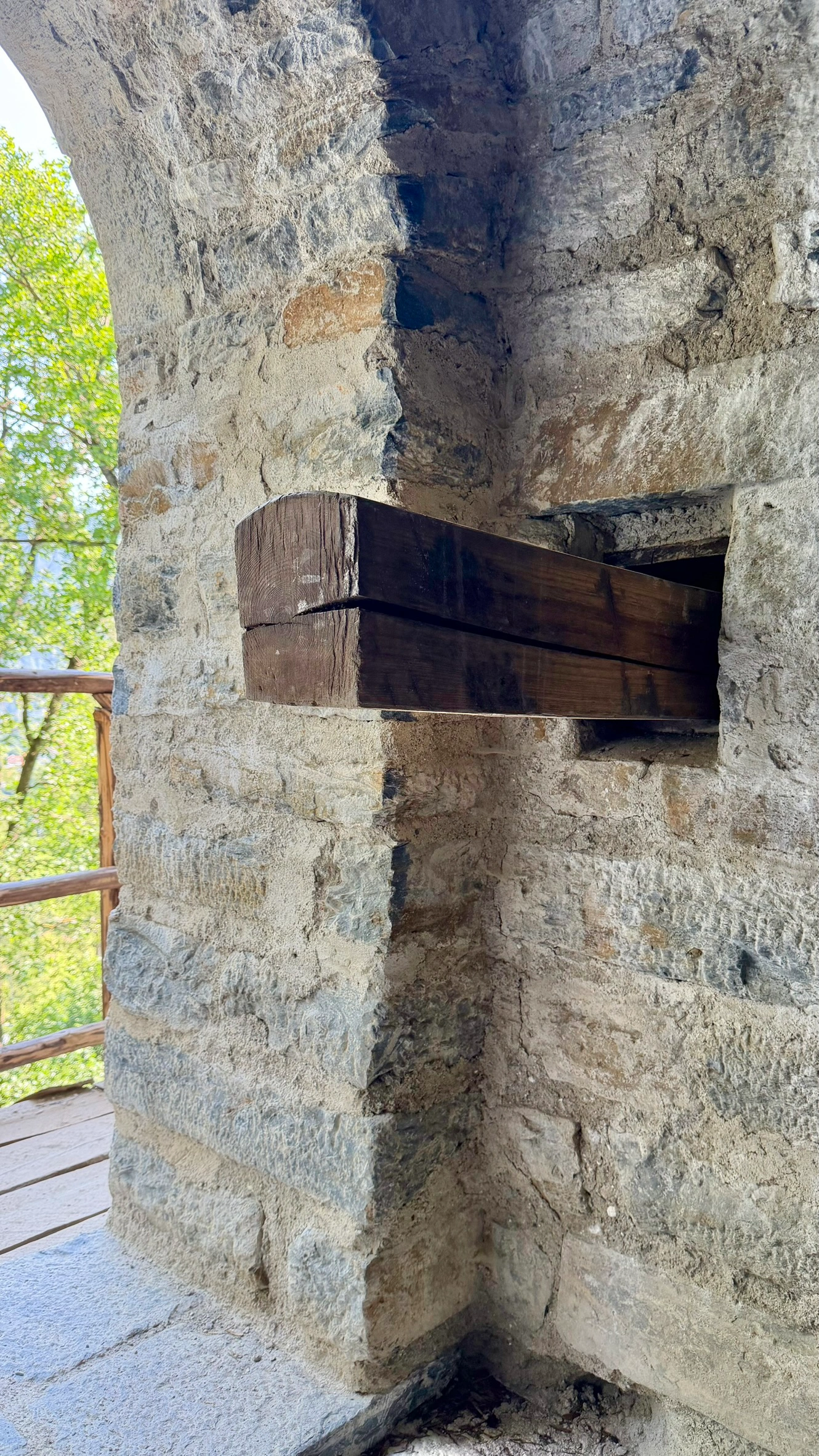 Ein zugeschnittener Holzbalken ist in eine rechteckige Mauernische eingesetzt. Ansicht von innen.