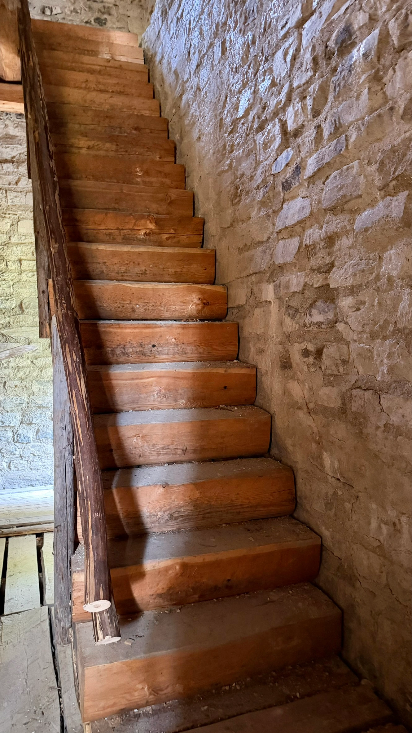 Die Holztreppe auf der Eingangsebene führt zur darüberliegenden Wohnebene.
