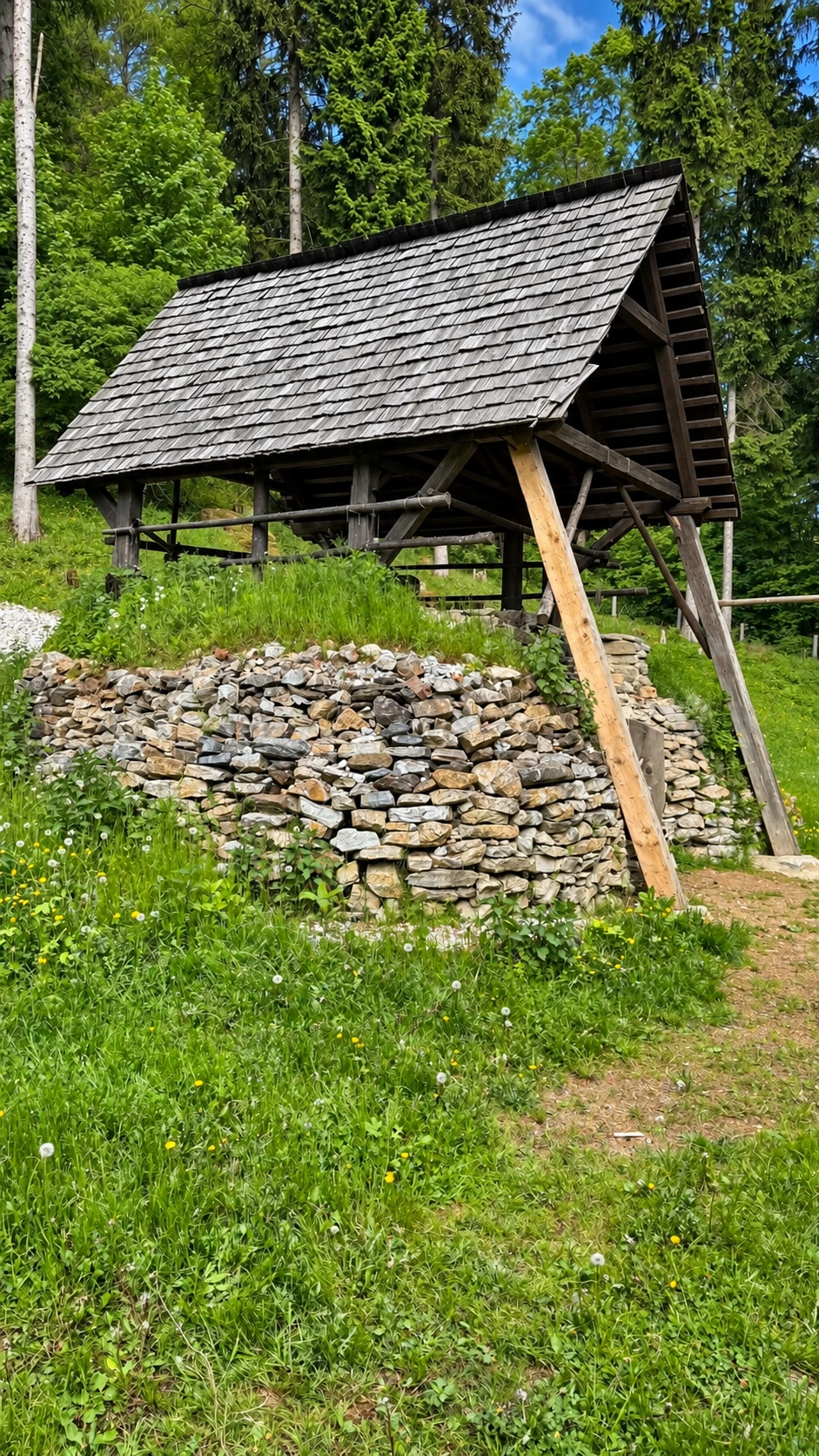 A roofed shelter protects the lime kiln from rain while allowing ventilation and access during lime production.