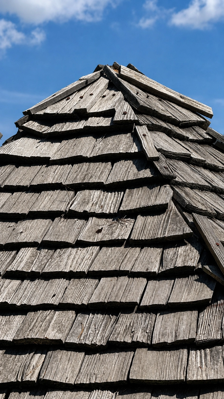 The roof is covered from the eaves upwards using overlapping rows of shingles.