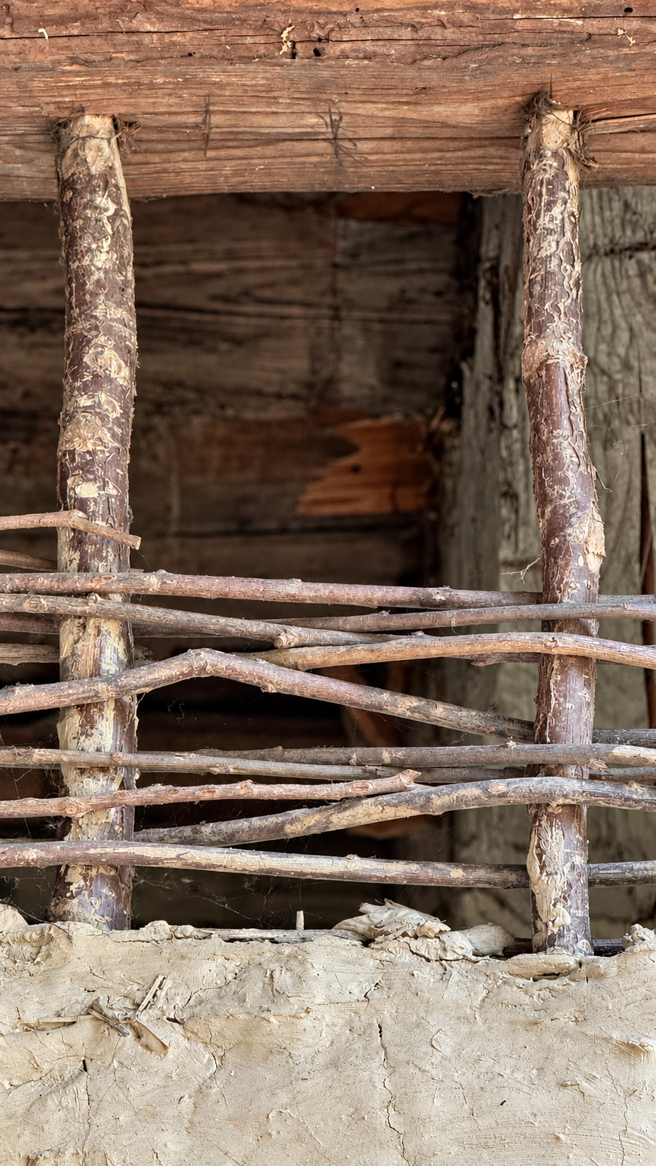 Vertical staves are fixed to the beam above. Horizontal woven rods complete the framework.